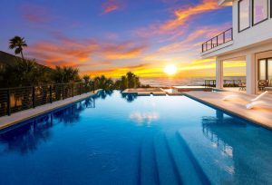 beachfront pool home with sunset over pool