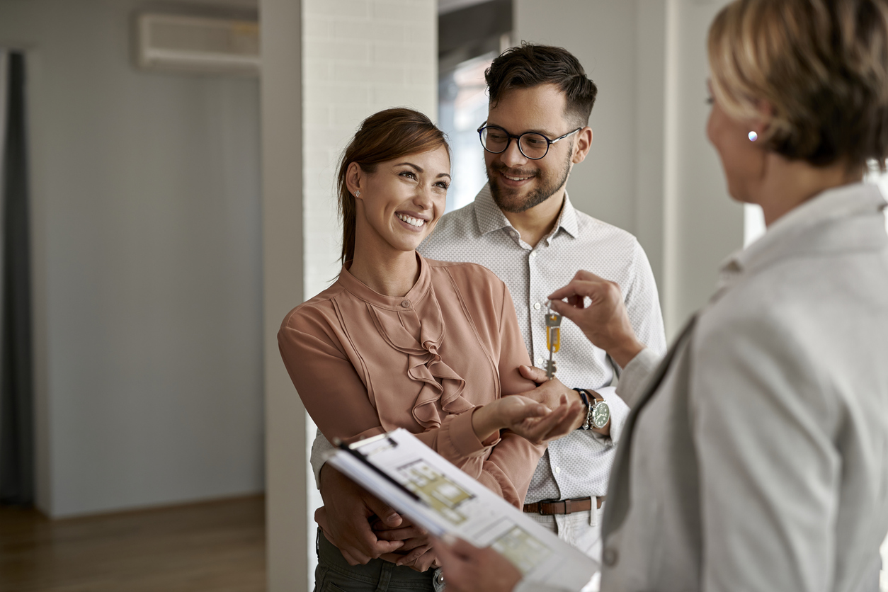 Young couple owning a home and getting keys from real estate agent