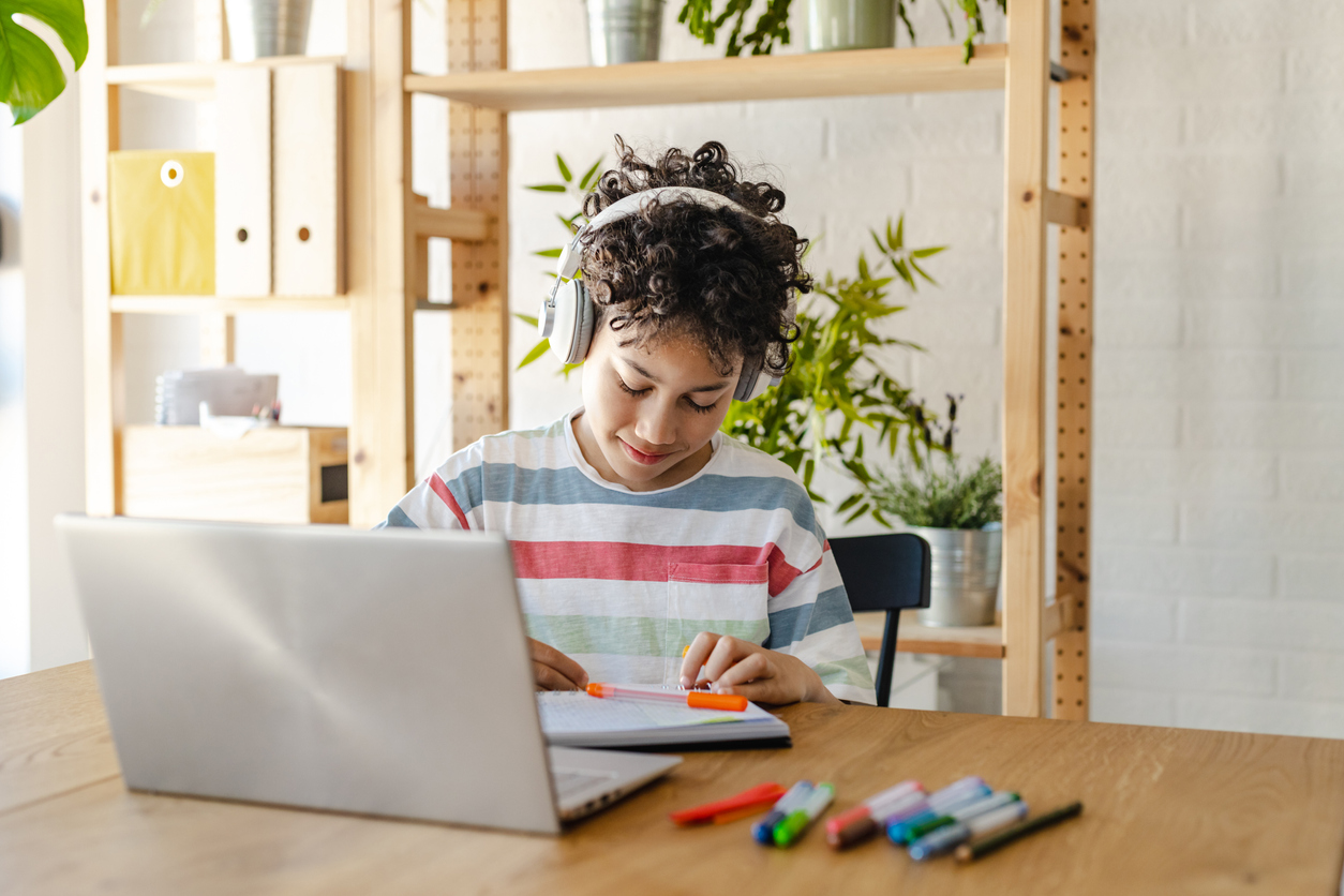 Little boy doing his assignment using a laptop at his homework station