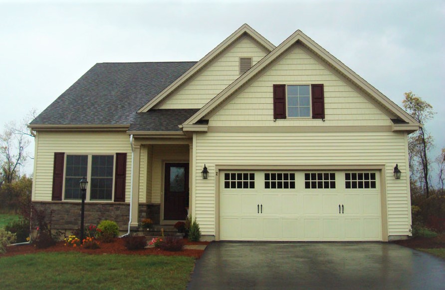 The front of a cream colored house with tan stone veneer and maroon shutters