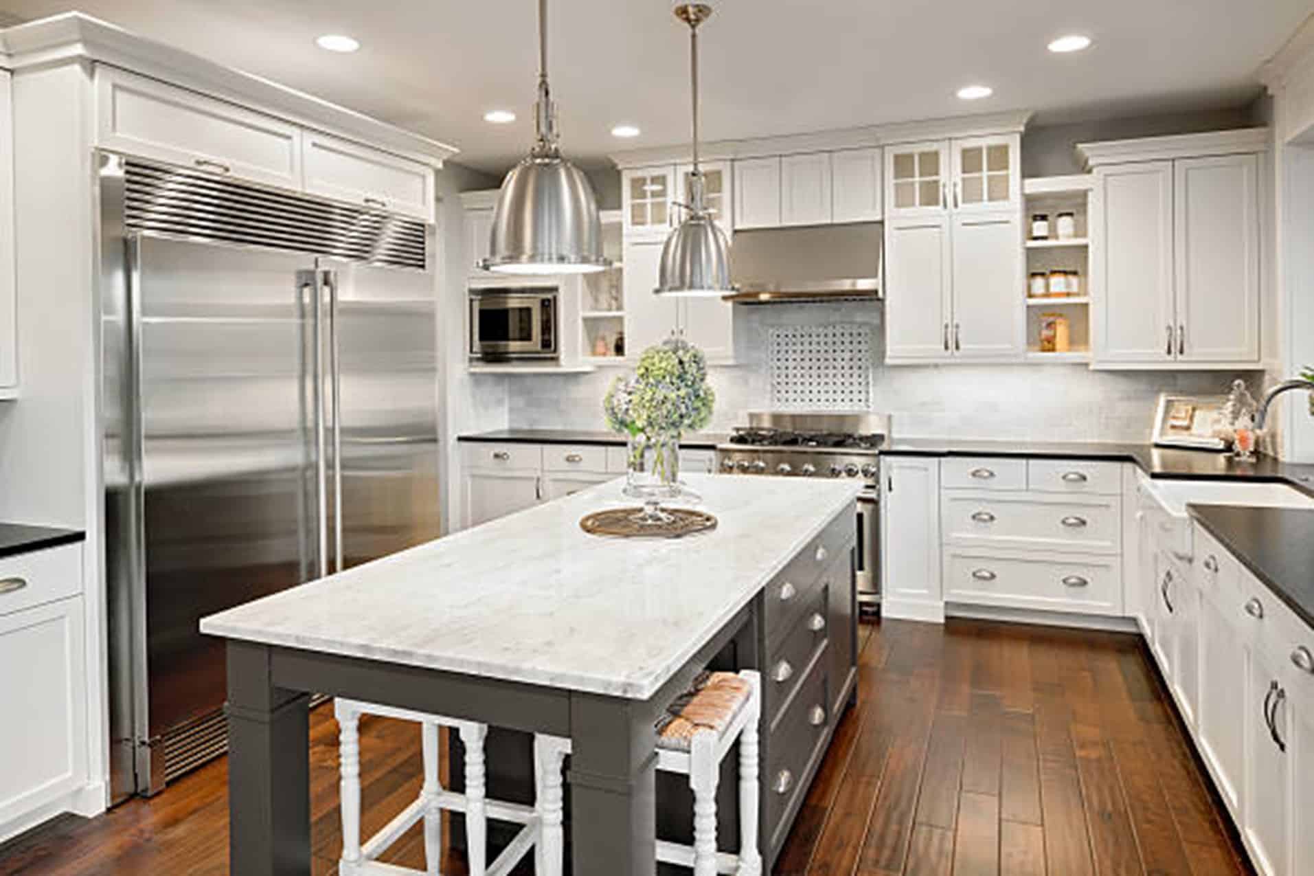White Kitchen with dark countertops with Stainless Steel Appliances and an dark island with a white countertop