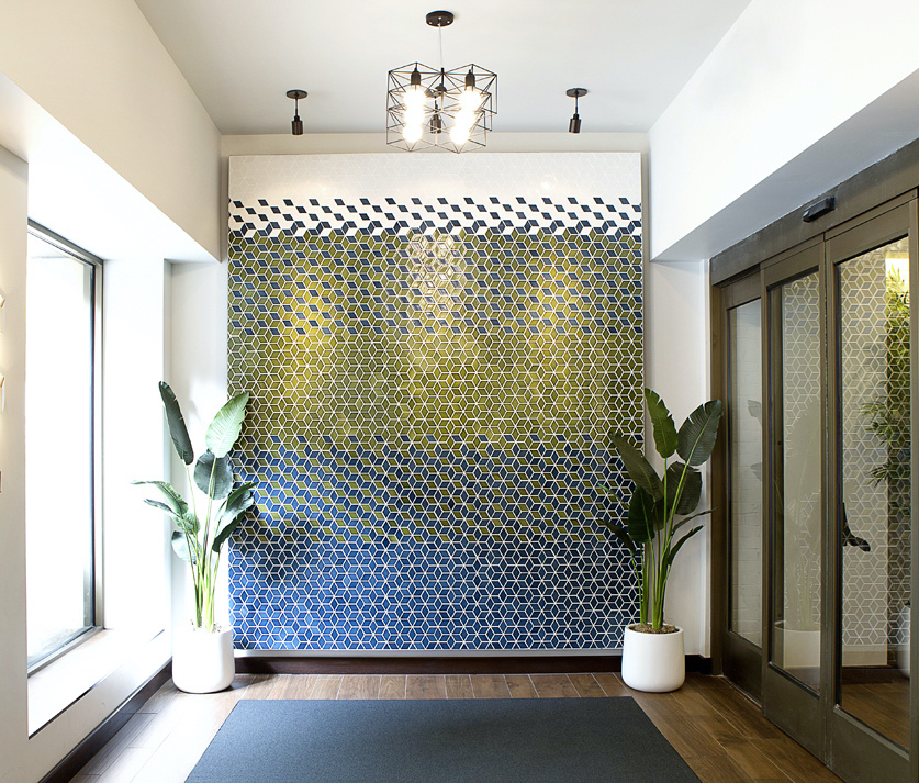 A gradient tile art piece of geometric patterns composed of sage greens and blues adds texture to the space