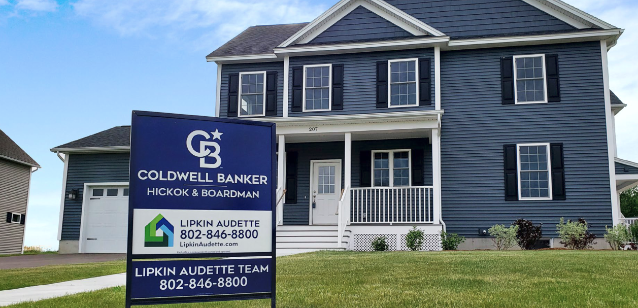 A home for sale with a real estate sign on the front yard