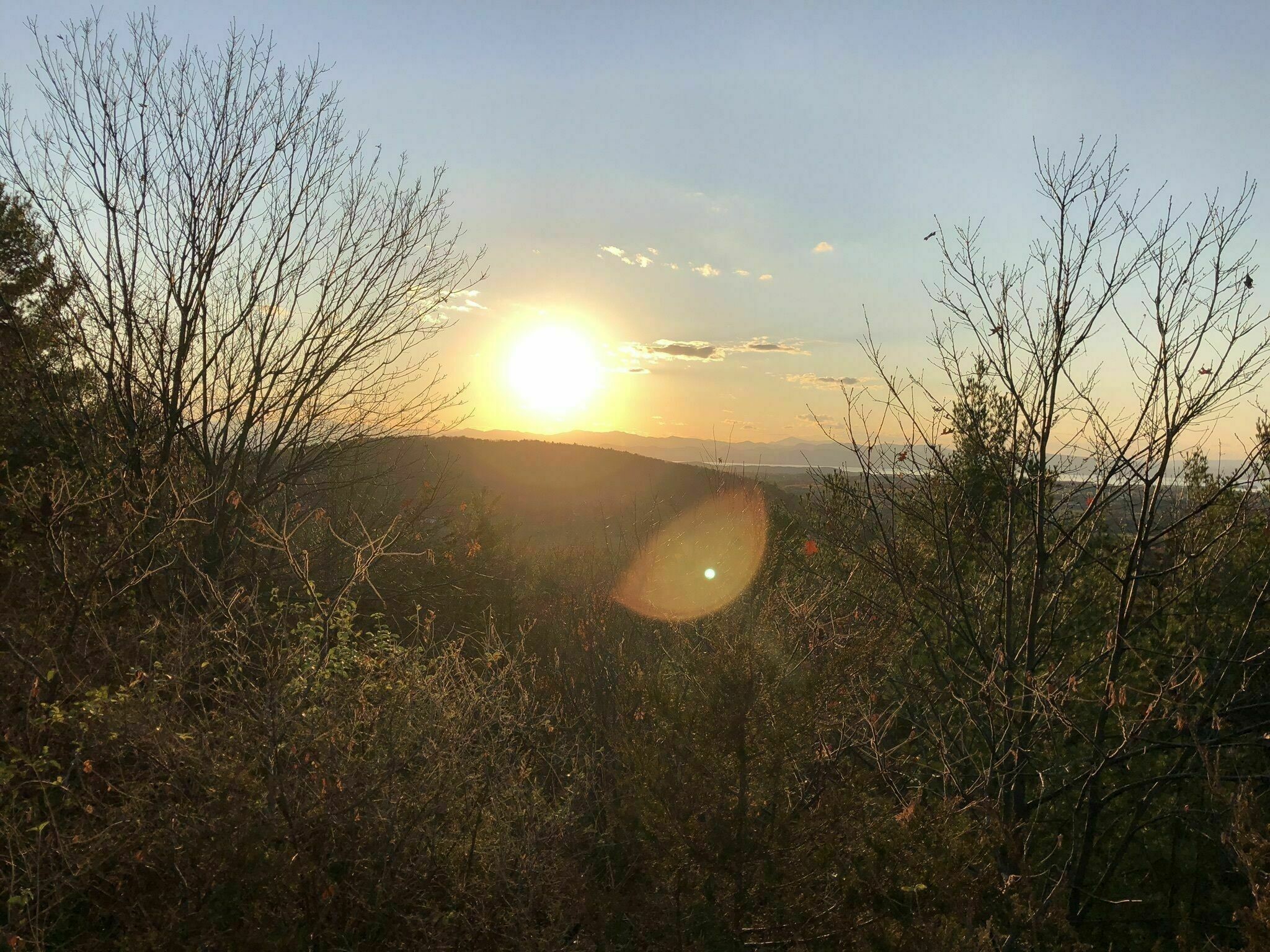 Sunset over a hilltop with mountains in the backdrop