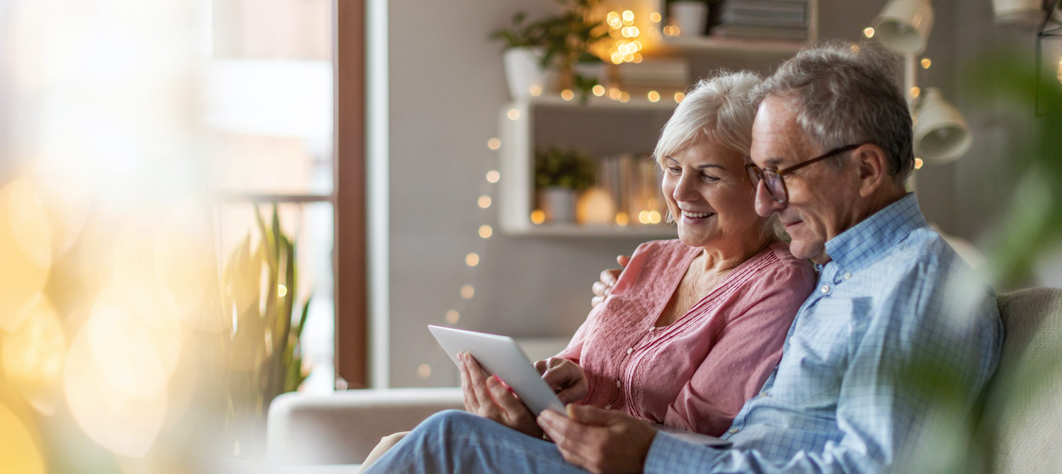Elderly couple looking at tablet in living room