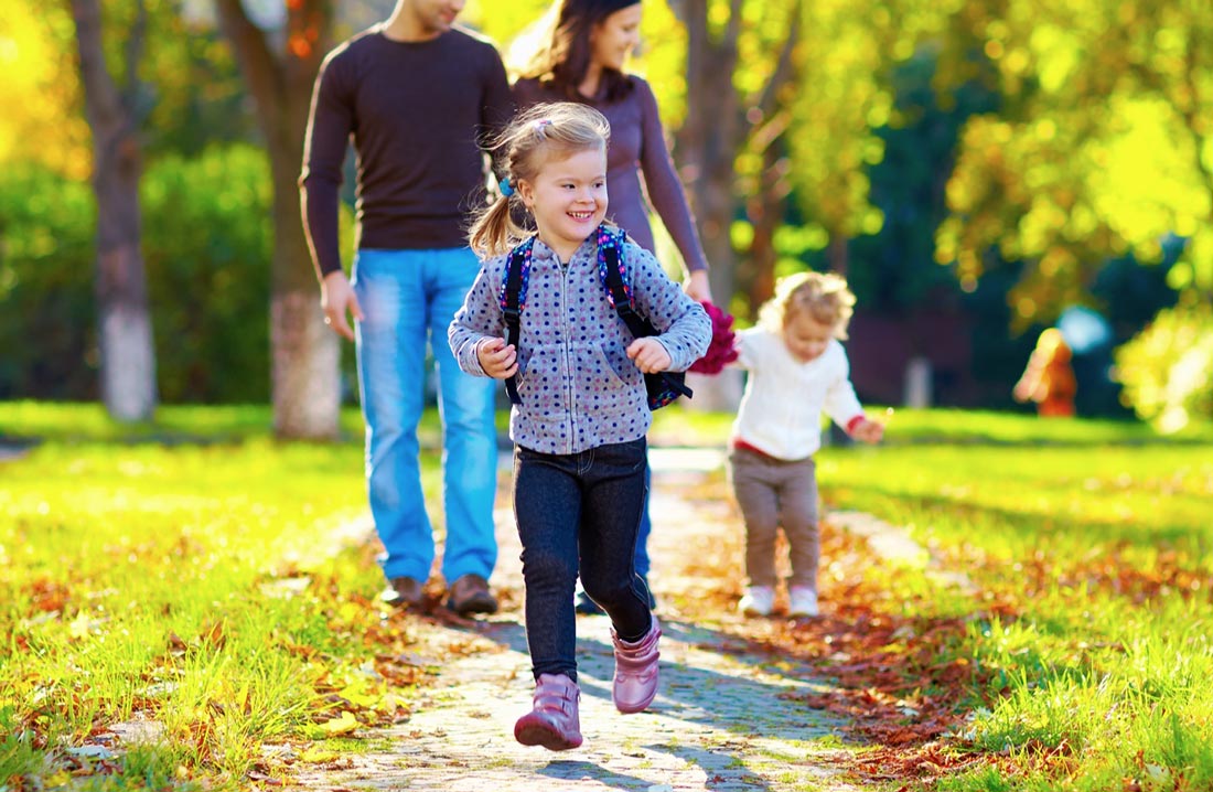 child walking in park with backpack