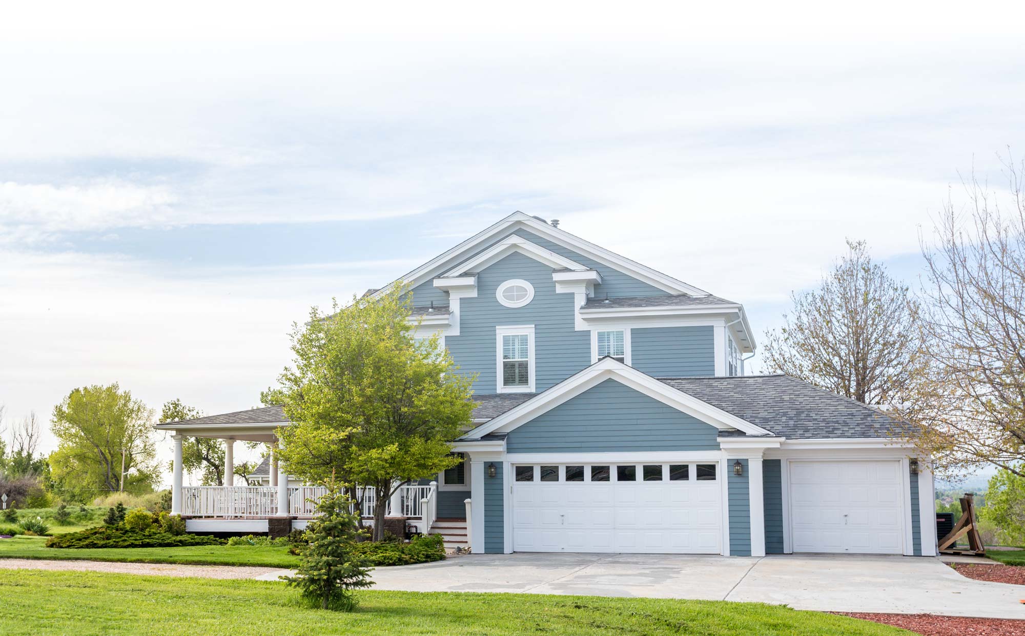 Large grey house in neighborhood with tree in front yard