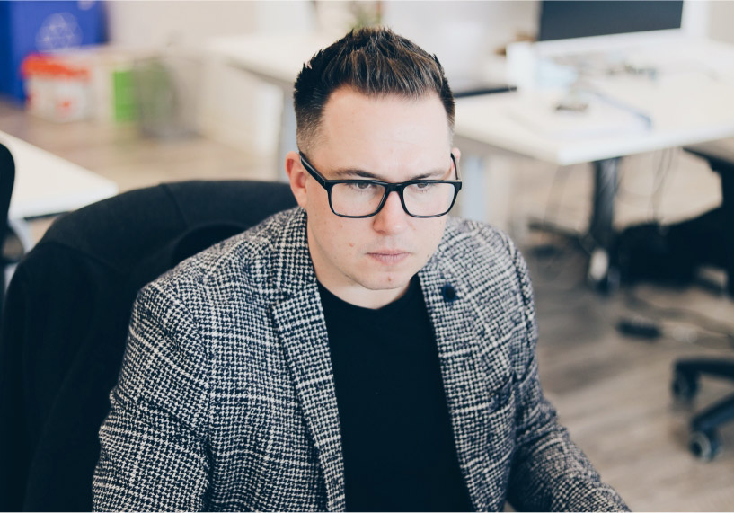 Man wearing suit jacket and glasses sitting at desk in office