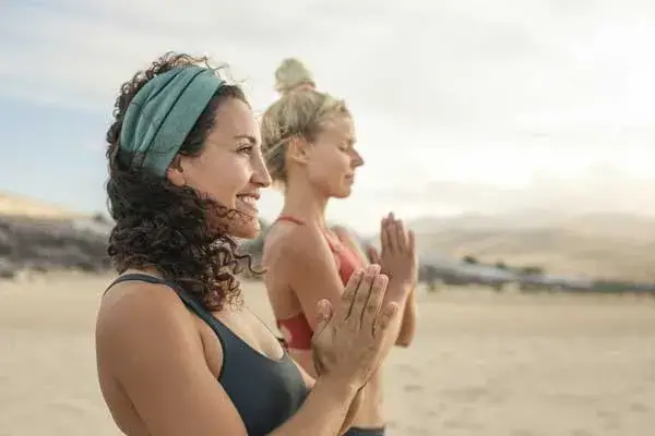 two women doing yoga on the beach
