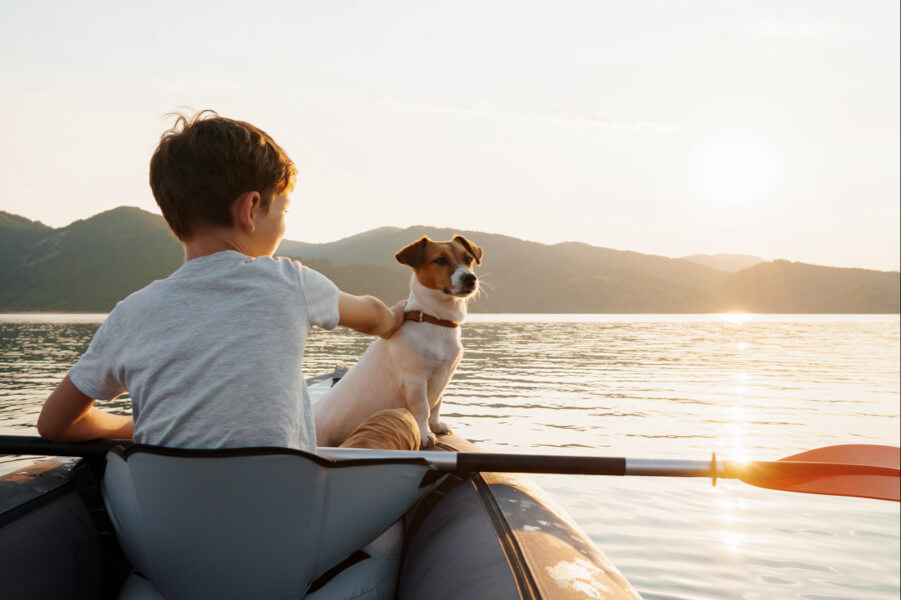 boy with the dog on the boat is watching for the sundown