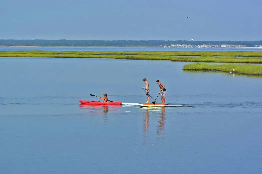 Three people kayaking and paddle boarding on the ocean in High Bar Harbor, New Jersey