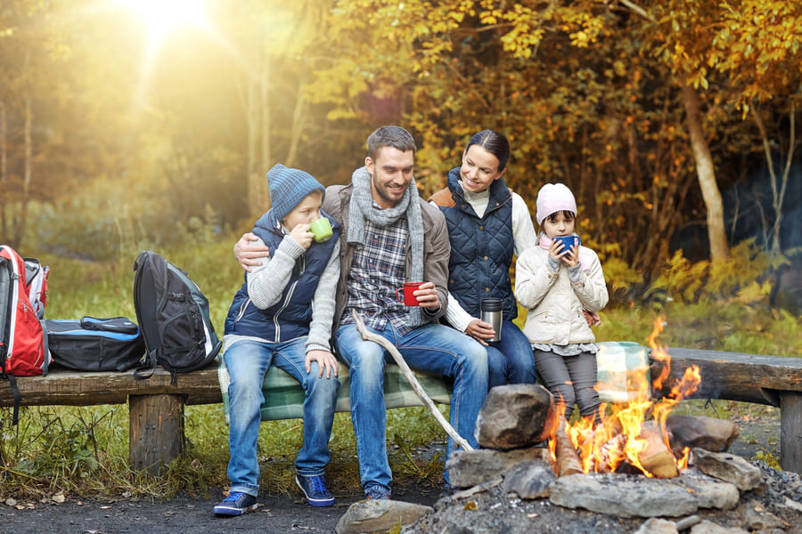 happy family sitting on bench at camp fire