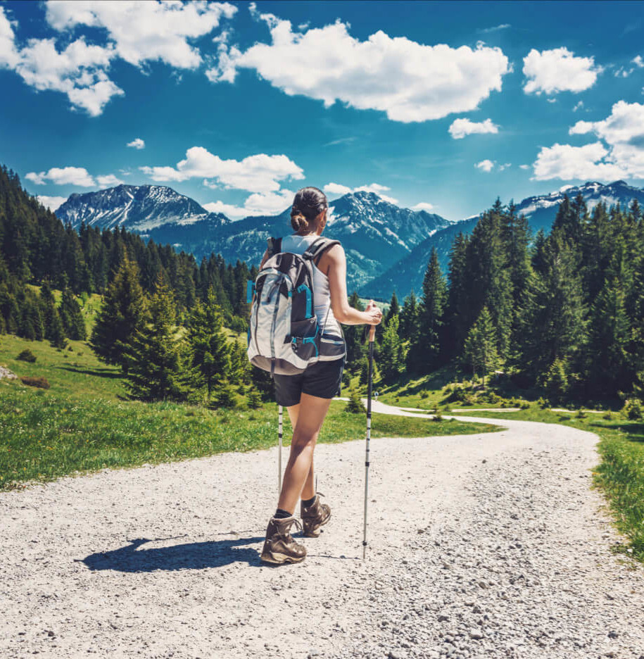 the woman is walking in the forest near the mountains