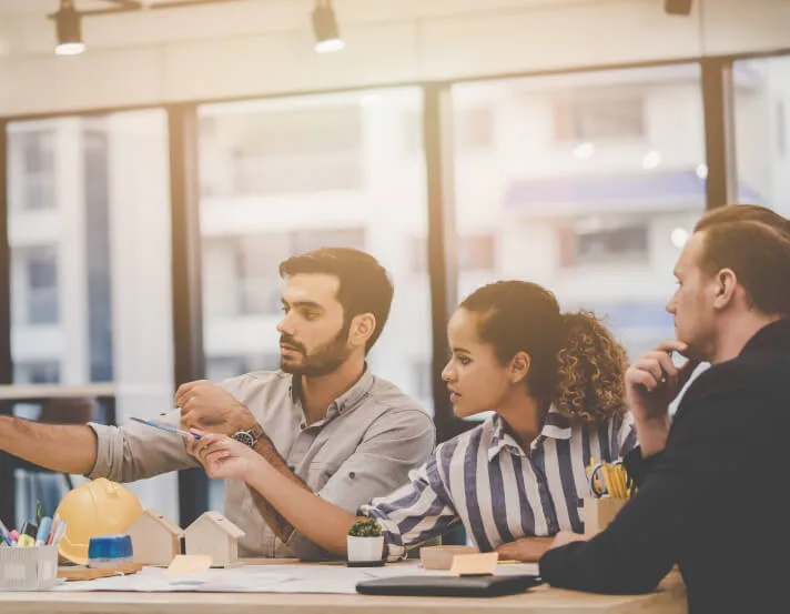 three businesspeople having a conversation around a table