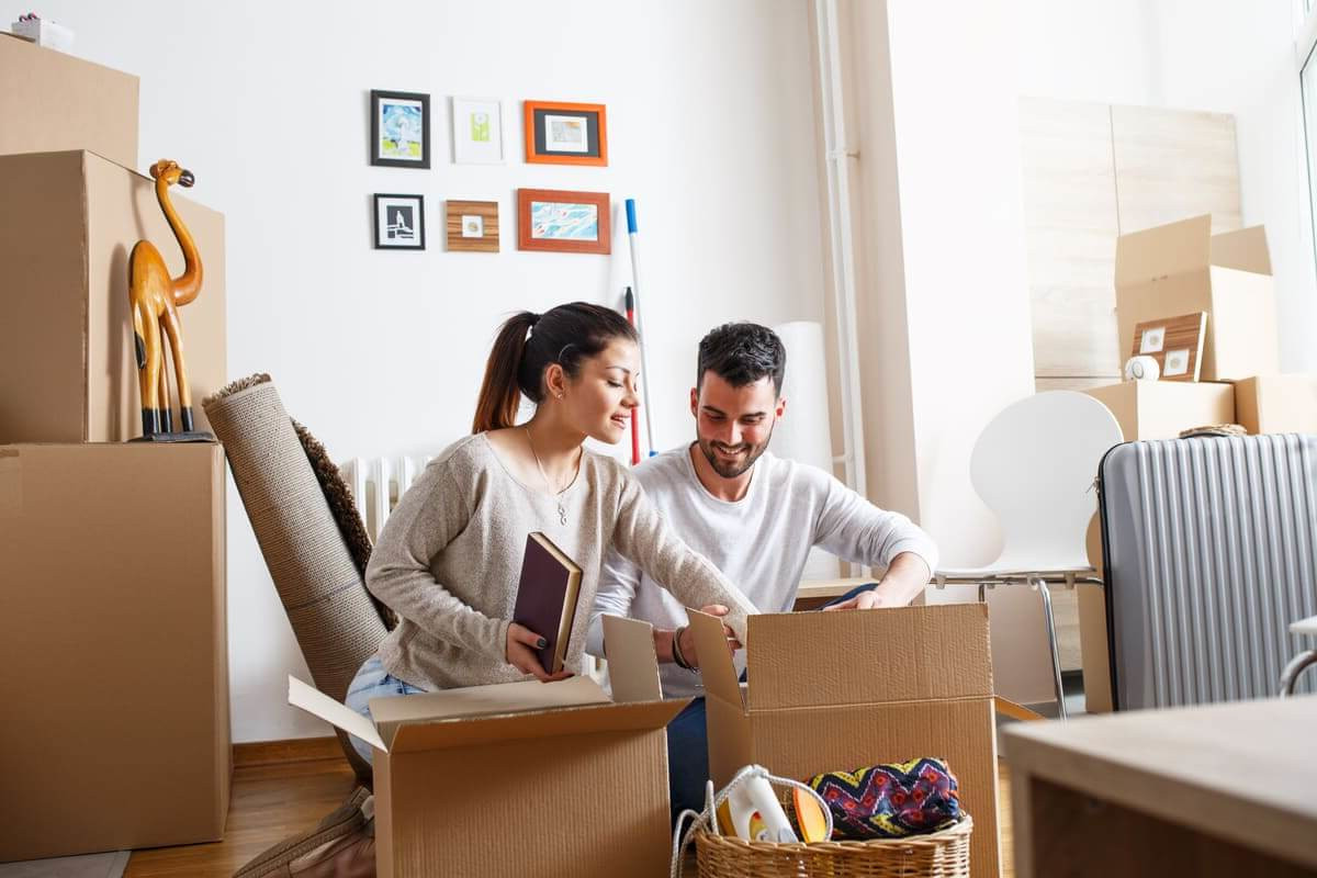 Young couple unpacking cardboard boxes at new home.Moving house
