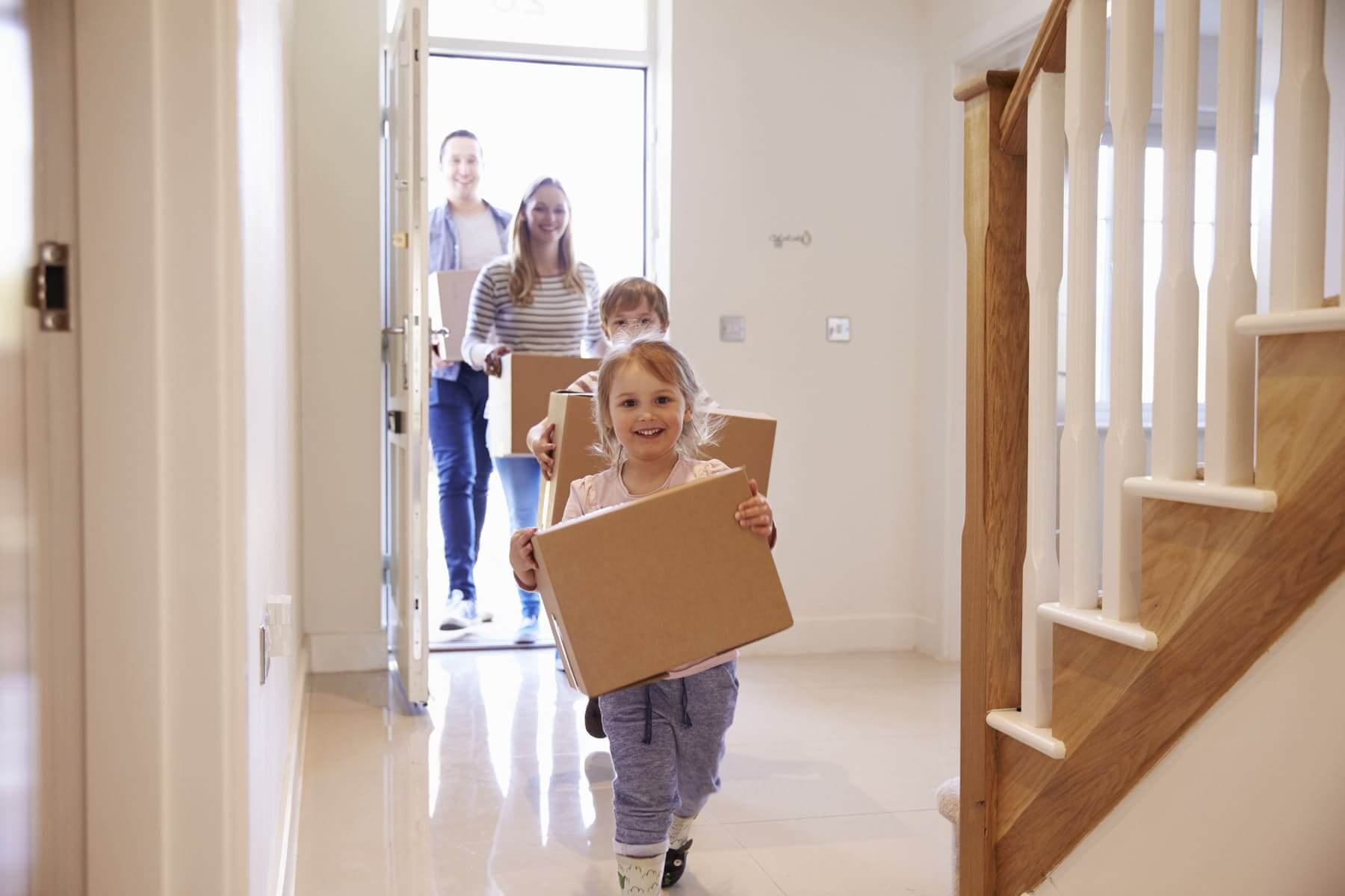 A happy family is carrying boxes into a new house.