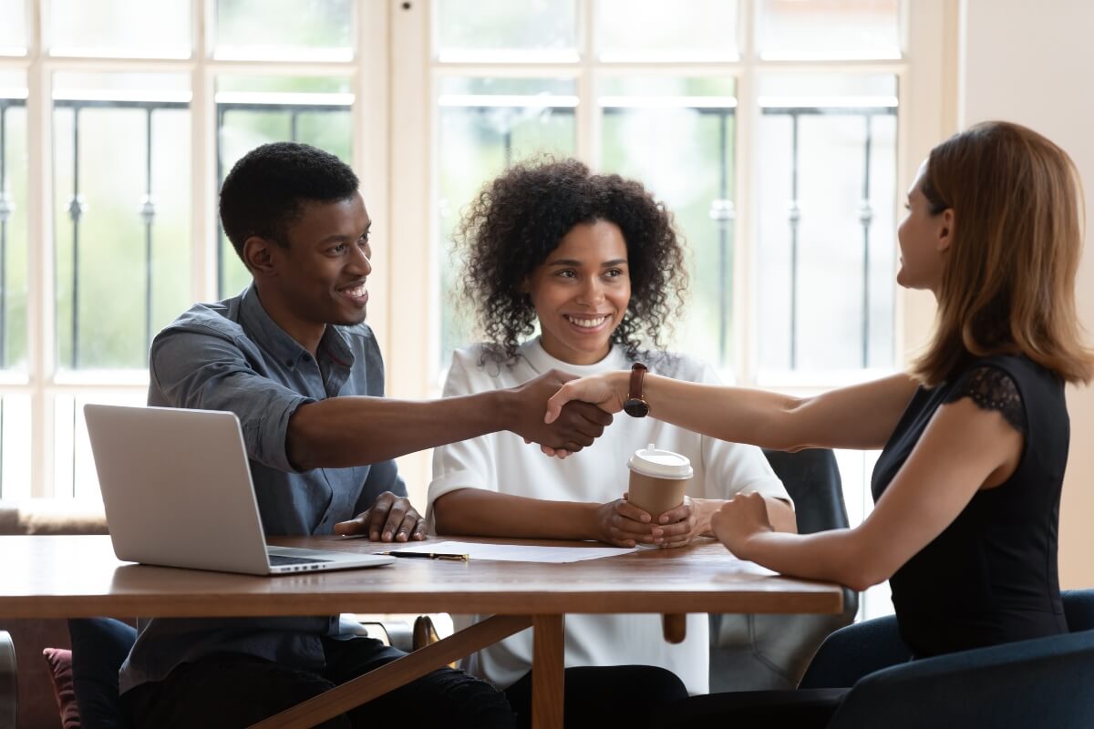 Happy African American family handshaking with realtor at meeting
