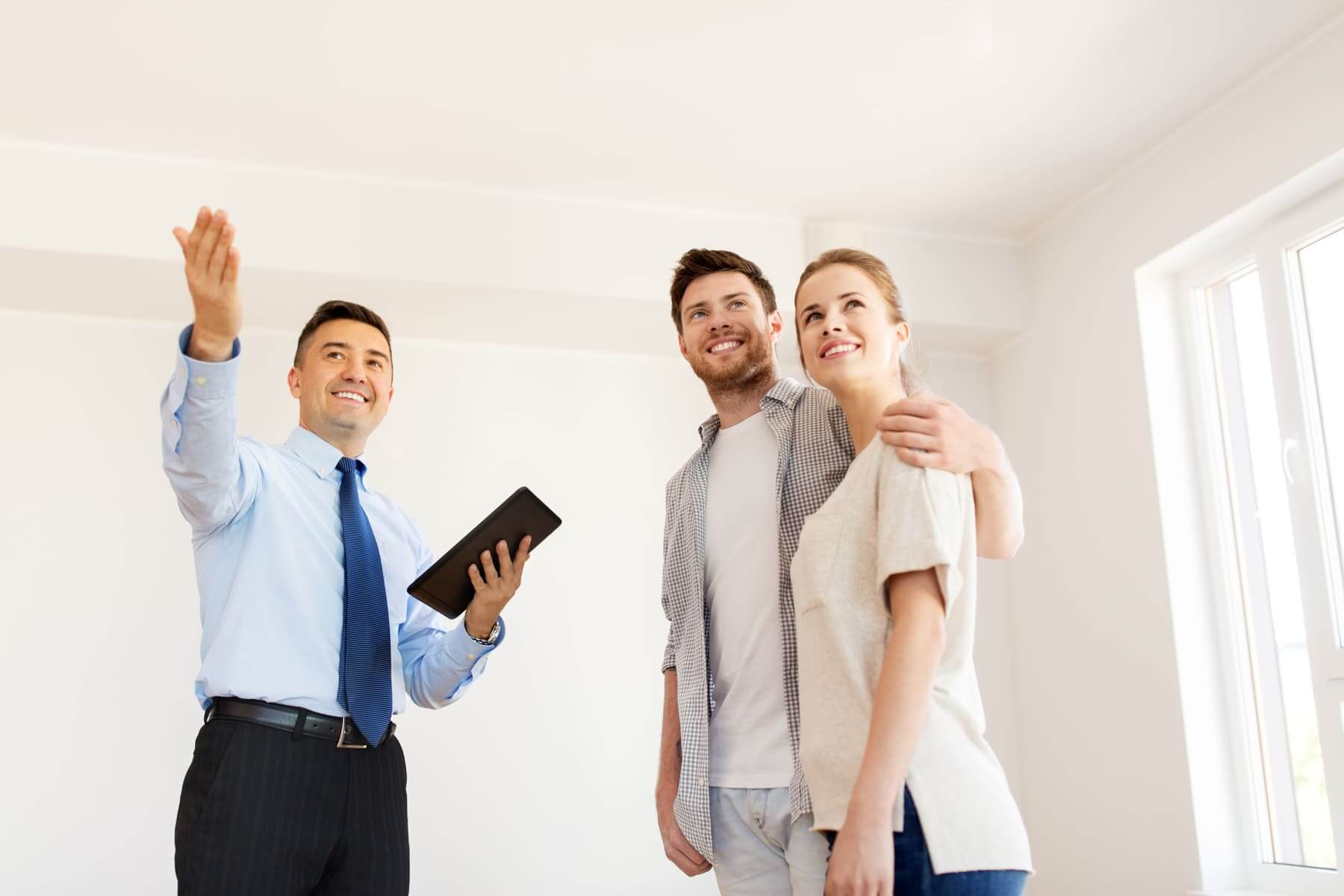 couple and realtor with tablet pc at new home