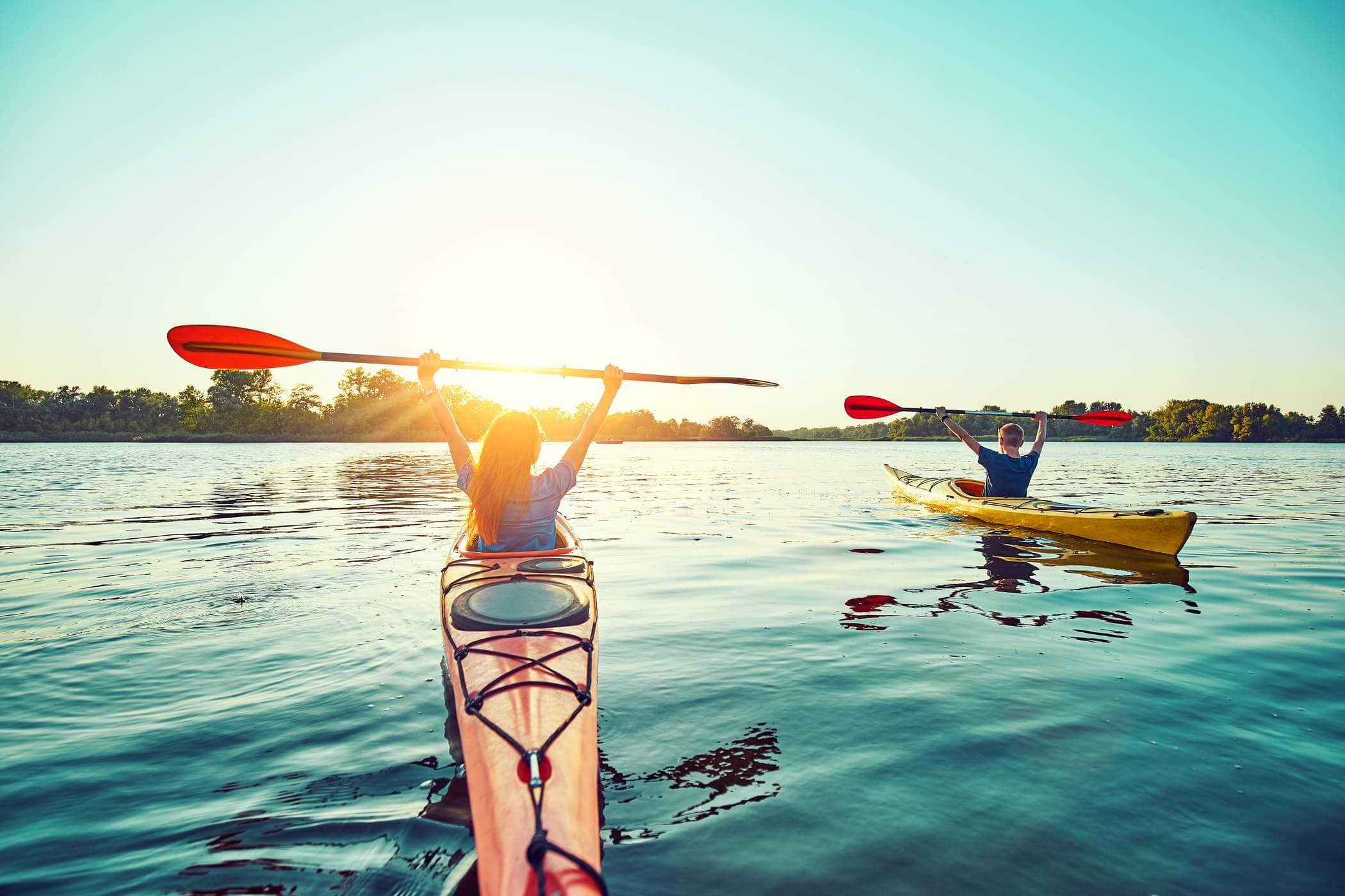 People kayaking during sunset in the background.
