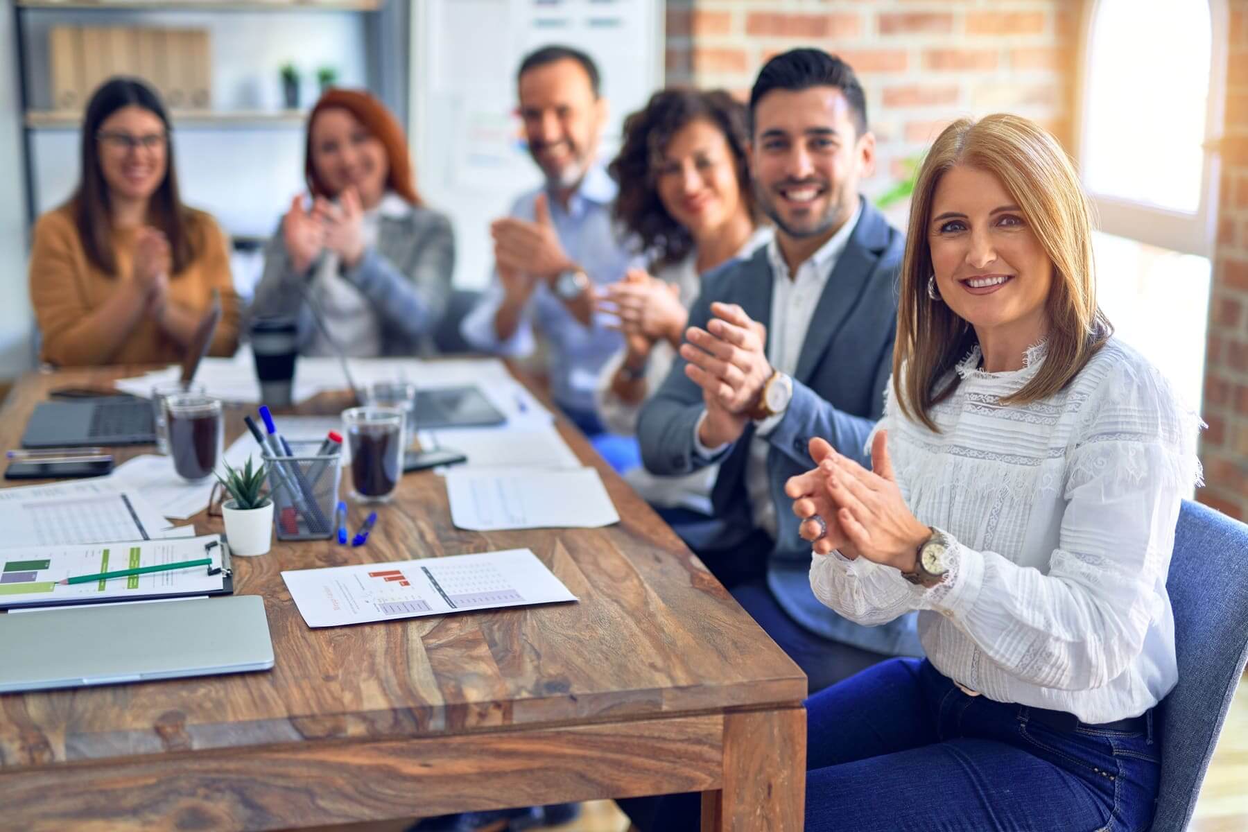 Group of coworkers smiling and applauding at the office
