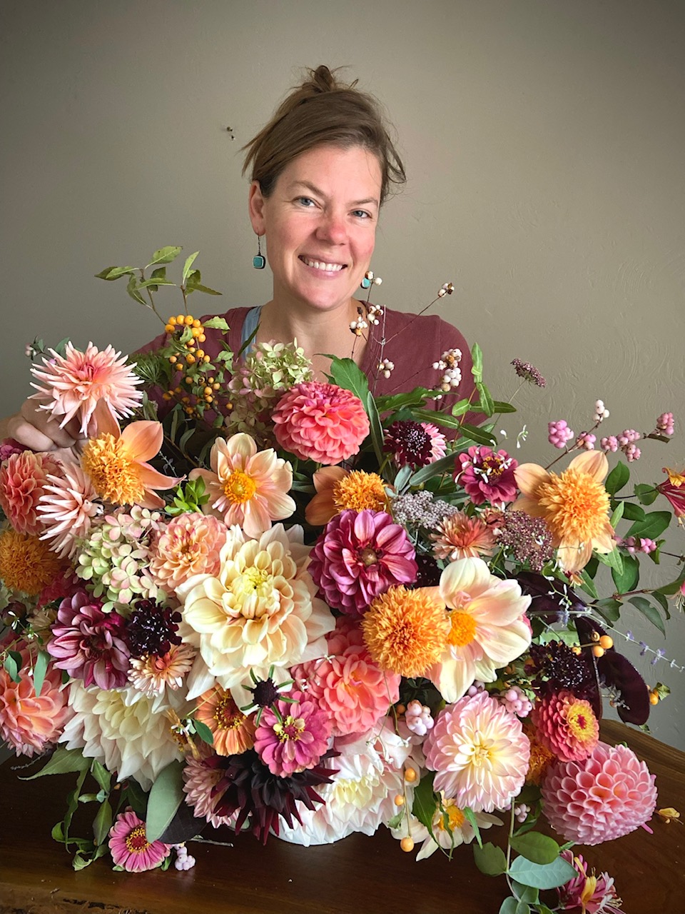 gardener holding a large bouquet of pink and orange flowers