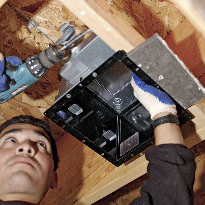 2  When positioning the fan, a scrap of drywall acts as a stand-in for the finished ceiling.