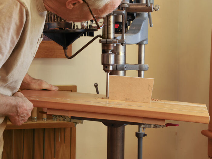 a piece of sharpened rod mounted in the drill press chuck with a bevelled block next to the rod