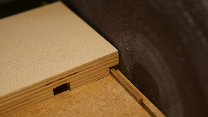 A piece of wood next to the sanding disc. The wood has a rabbet cut into the edge which will stop on the fence of the table beneath it.