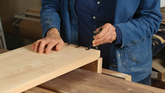 Transfer the tails. With the case top held vertically in a vise (below), lay the corresponding side board onto the end and transfer the tails to the top.
