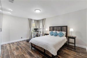Bright, corner guest room with ceramic plank flooring and custom closet.