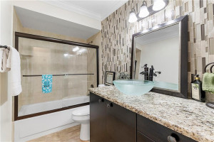 NEW guest bath boasts granite vanity with full glass tile backsplash, crown molding and tub with tile to the ceiling.