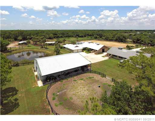 Exterior Front. Aerial showing the 2 barns with attached 2/2/2 home and 1/1 apartment, pond, riding arena, utility building and round pen