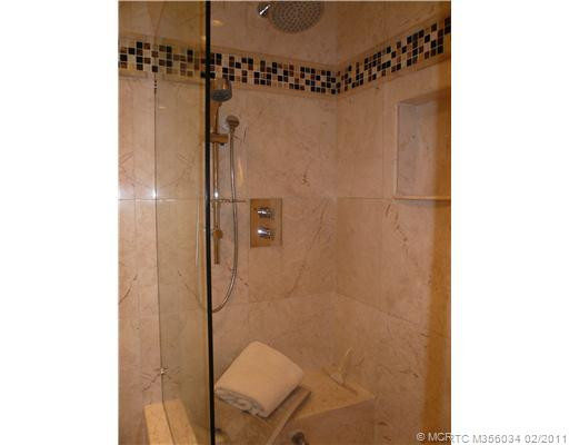 Master Bath/Spa. Walk-in marble shower features Italian Aqua Brass Rainhead & Handheld fixtures, body jets on opposite wall, marble seat, inset marble toiletries shelf, frameless glass enclosure & door