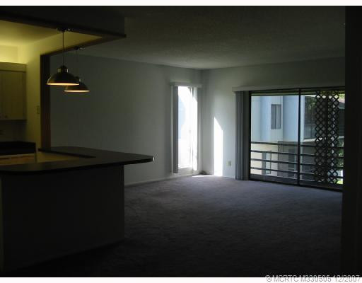 Living Room. Open kitchen with breakfast bar looks out to living room and patio with large side window for light