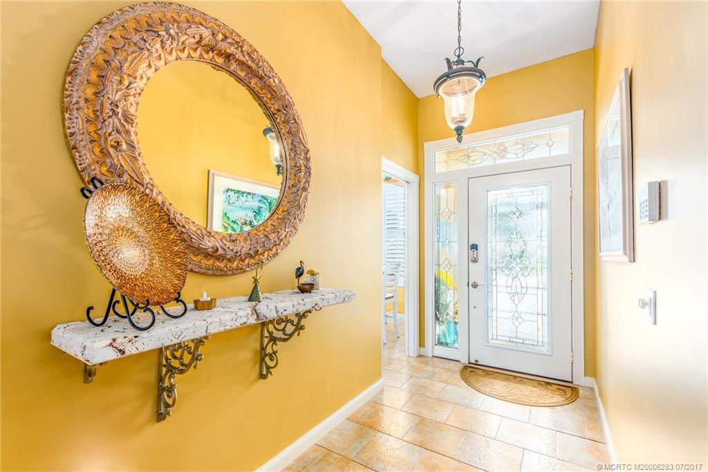Elegant Foyer with gorgeous coral stone shelf, upgraded tile flooring & designer lighting fixture.