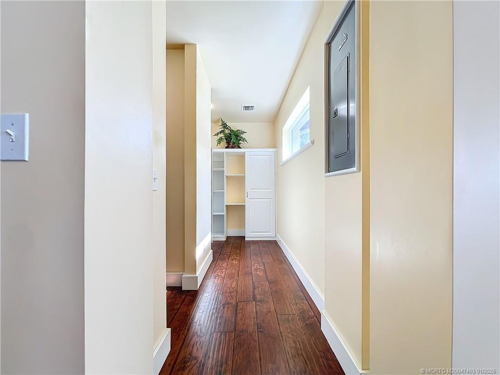 This is the laundry room off the kitchen and great room areas. Laminate floors the first opening to the left is shelves for storage the 2nd left is washer and dryer with storage and folding area and you can hang your clothes . To the right is the electric box and a impact window. look at how light and bright it is. Fresh paint.