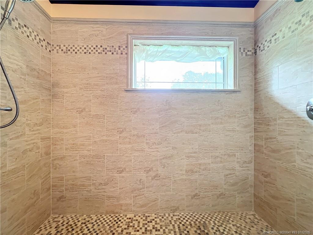 Wow! what a primary shower, look at the beauty of the tile work and impact window looks out the at the trees and sky. double head shower.