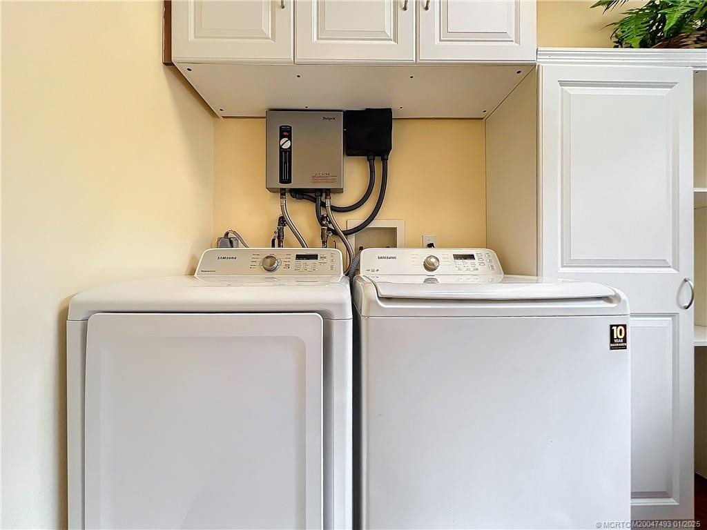 washer and dryer top loaders, you can see behind washer and dryer is the tankless hot water heater. Lots of cabinets for stoarage.