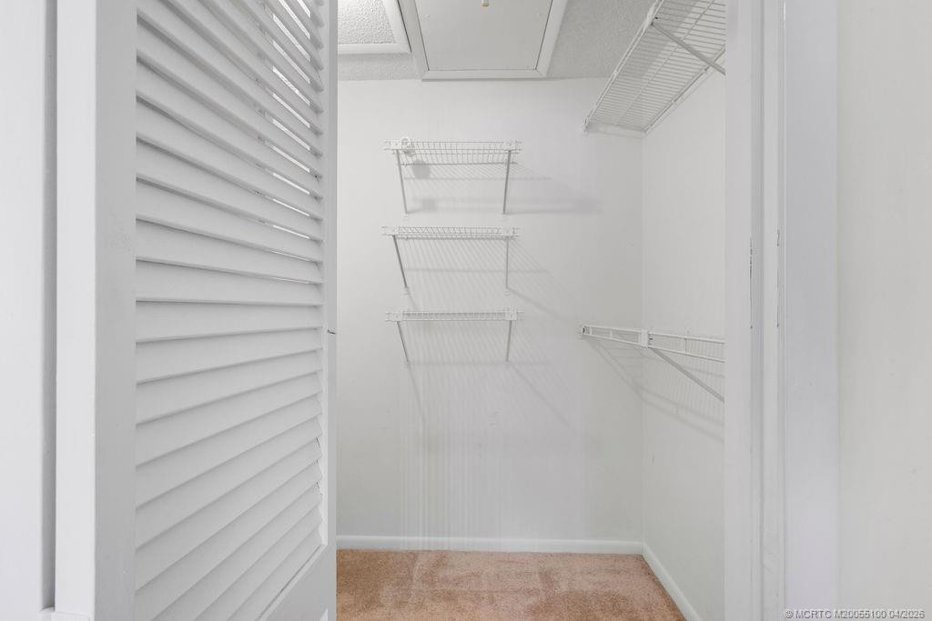 Walk in closet in primary bedroom with pull down stairs & extra storage space