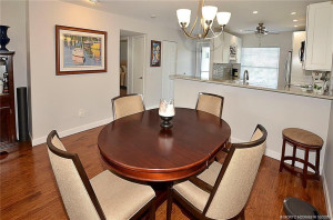 Spacious dining area with wood-look flooring opens to a beautifully updated kitchen featuring granite countertops, tile backsplash, bar seating, and recessed lighting.