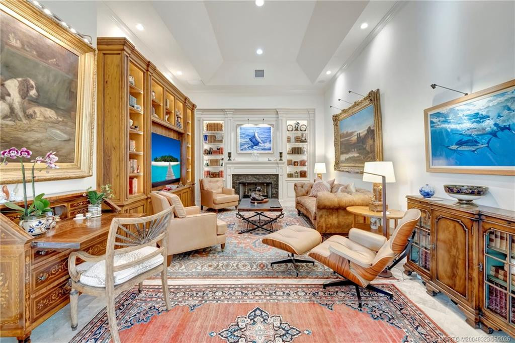 Elegant and inviting den off foyer with fireplace and custom cabinetry