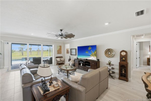 Bright and spacious open-concept living area features elegant tile flooring, crown molding, and expansive sliding glass doors that seamlessly connect indoor and outdoor living spaces. Designed for comfort and entertaining, this inviting great room offers abundant natural light and relaxing views of the screened pool and private preserve beyond.