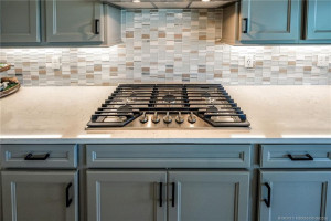 Chef-inspired kitchen features a premium gas cooktop, quartz countertops, upgraded cabinetry, and a stunning designer tile backsplash. Thoughtfully designed for both style and functionality, this elegant cooking space offers the perfect blend of modern finishes and everyday convenience.
