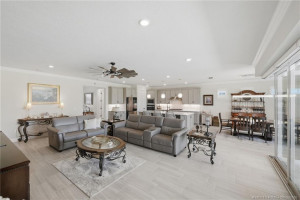 Expansive open floor plan offers seamless flow between the living, dining, and kitchen areas, creating the perfect space for entertaining and everyday living. Features include elegant tile flooring, crown molding, recessed lighting, and large sliding glass doors that fill the home with natural light and connect to the outdoor living area and pool.