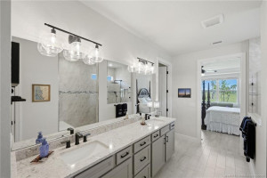 Luxurious primary bath features dual quartz vanities, upgraded cabinetry, designer lighting, and an oversized walk-in shower with elegant tile finishes and frameless glass enclosure. Spacious and beautifully appointed, this spa-inspired retreat offers comfort, style, and abundant storage.