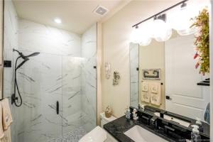 Beautifully upgraded guest bath features a walk-in glass-enclosed shower with designer tile finishes, modern fixtures, and elegant vanity with upgraded countertop and lighting. Stylishly appointed to provide comfort and privacy for family and overnight guests.
