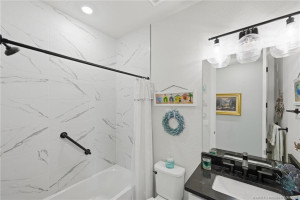 Stylishly upgraded full bath features designer tile surround, modern fixtures, upgraded vanity, and elegant finishes throughout. Thoughtfully designed to serve guests and secondary bedrooms with both comfort and contemporary style.