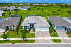 Exceptional aerial view showcases this beautifully positioned home with expansive preserve views and enhanced privacy in Del Webb at Tradition. Situated on a premium lot, the property features a screened pool, lush landscaping, paver driveway, and spacious outdoor living areas designed to capture the best of Florida living.