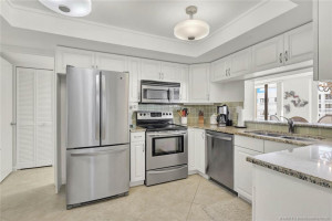 Stainless appliances with laundry facilities behind in hidden hallway