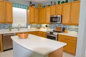 The kitchen has a center island at the forefront with Corian tops and beautiful oak cabinets. The tiled backsplash adds warth to the room. Upgraded SS appliances